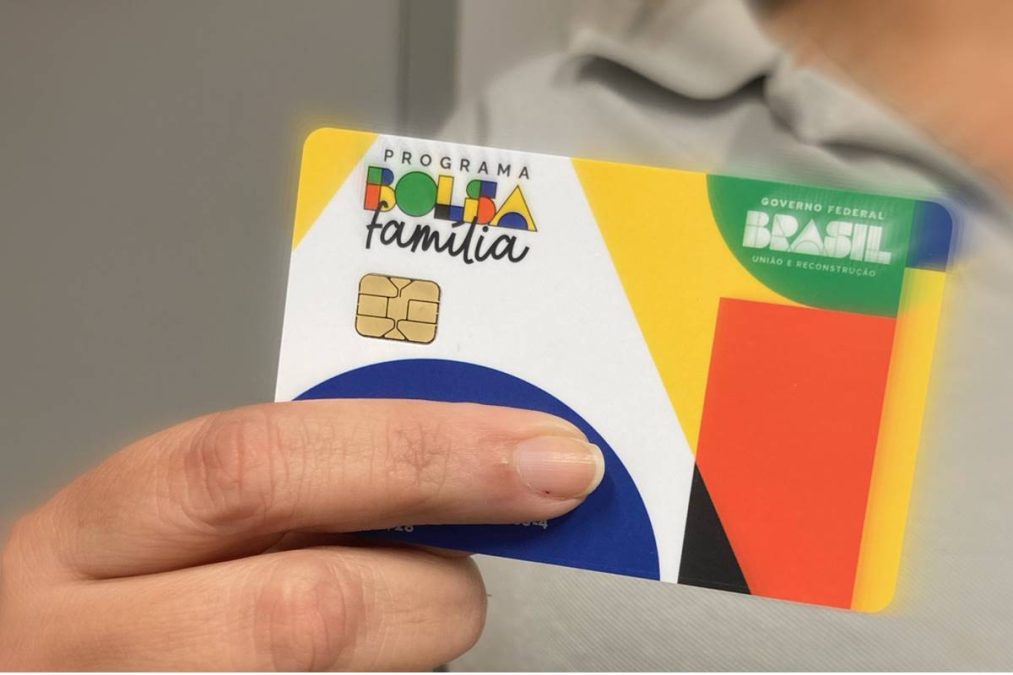 Pessoa segura cartão do Bolsa Família colorido