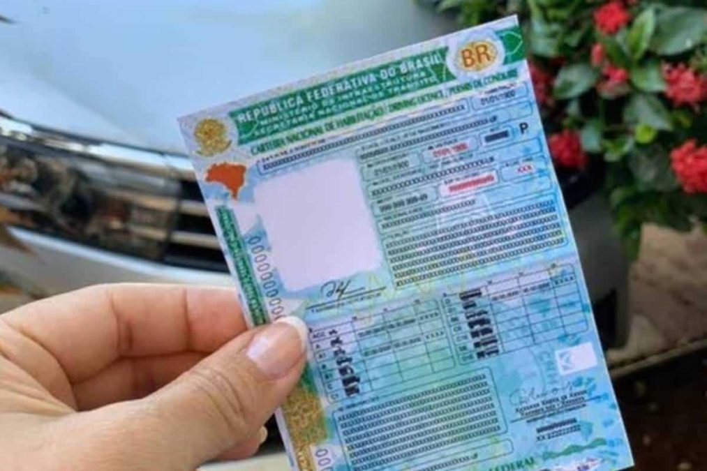 Pessoa segura CNH em destaque sobre carro