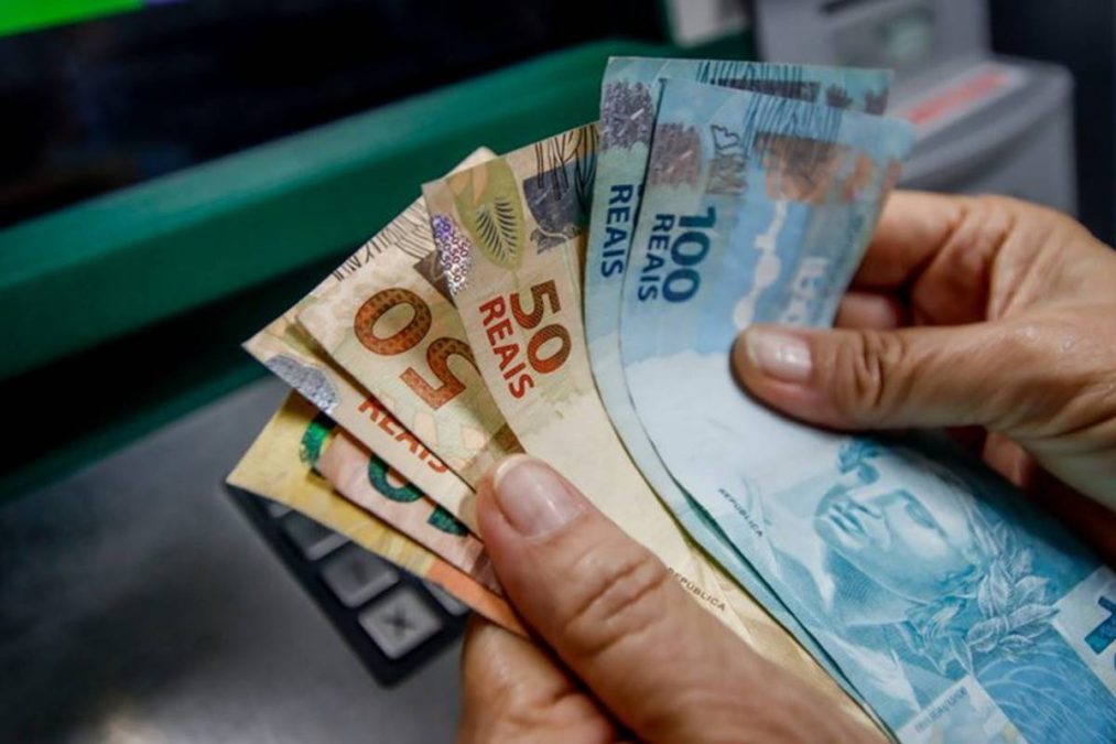 essoa segura notas de reais após receber décimo terceiro salário