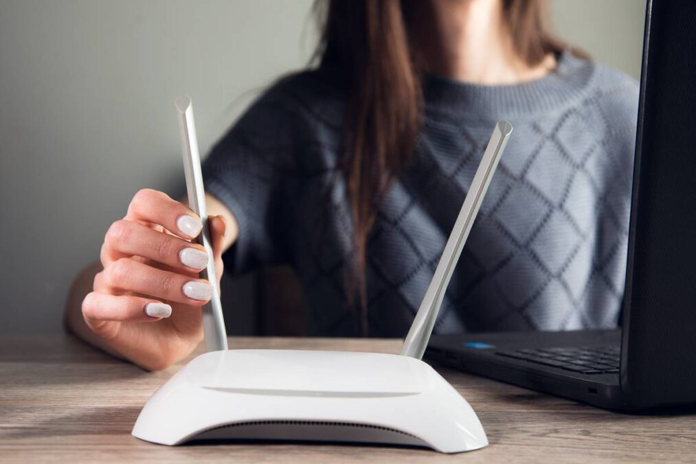 Mulher ajustando roteador em casa para resolver Wi-Fi lento