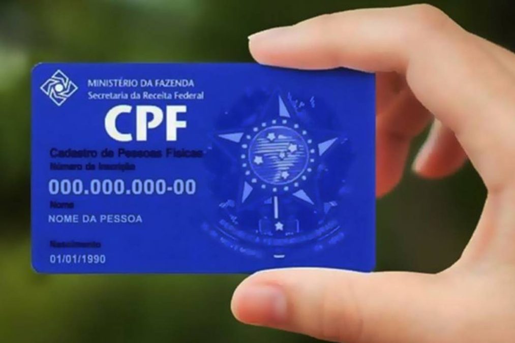 Mão segurando cartão azul do CPF na nota fiscal