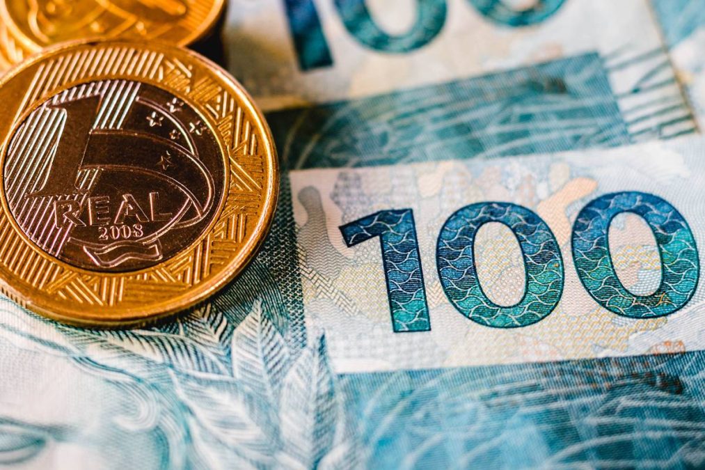 Moedas e cédula de real do adicional salário.