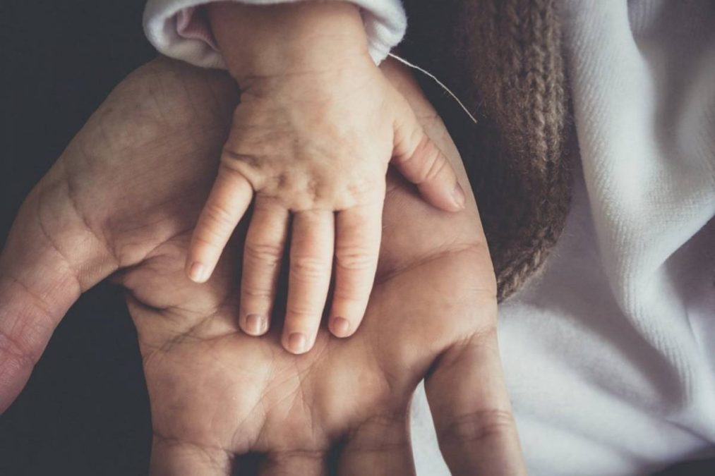 Mão de pai e filho na licença-paternidade
