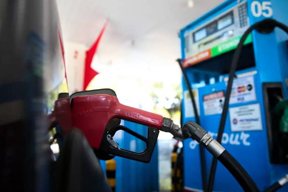 Bomba de combustível abastecendo carro em posto de gasolina.